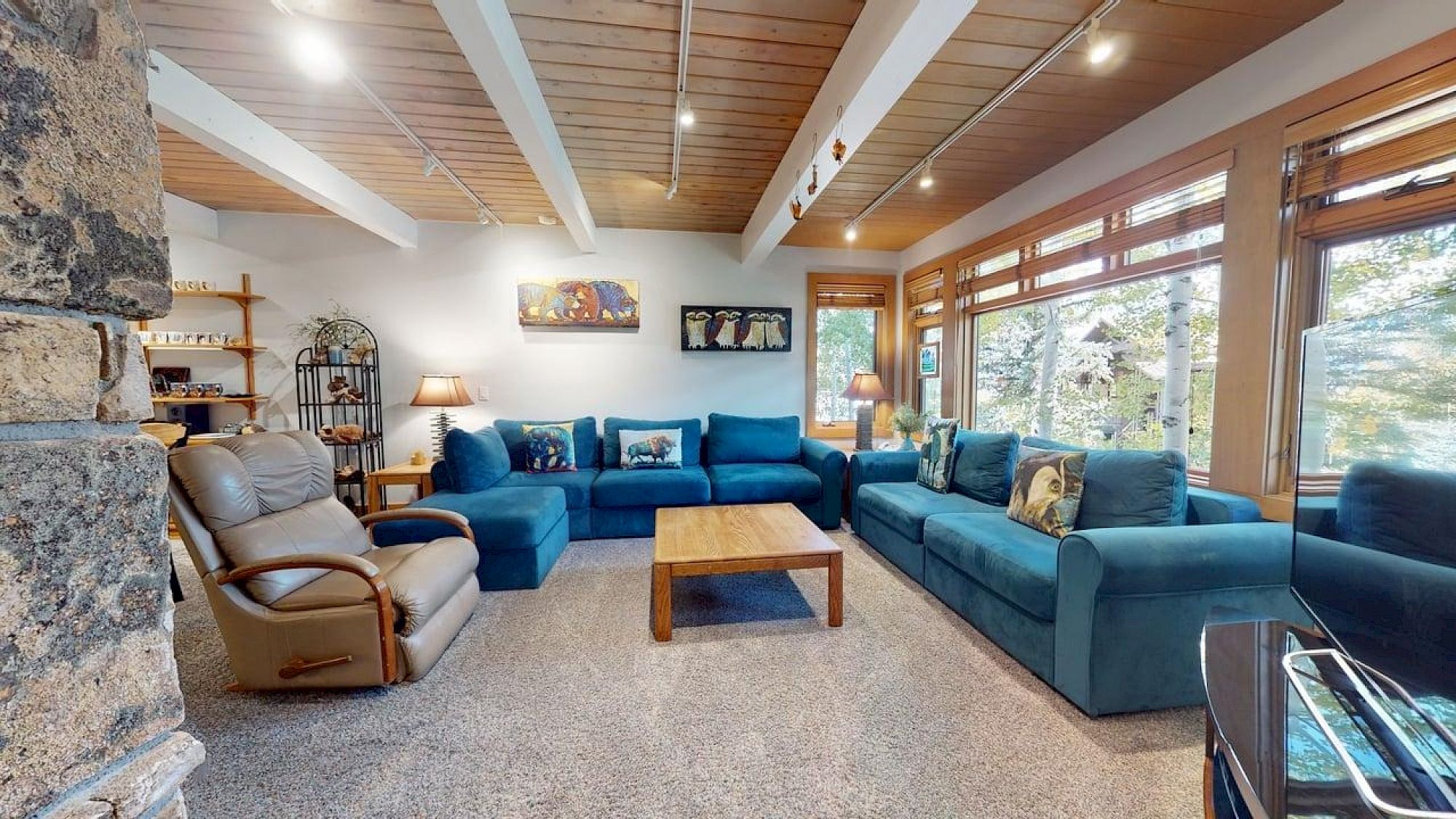 Sala de estar ampla com sofás teal e mesa de centro em madeira