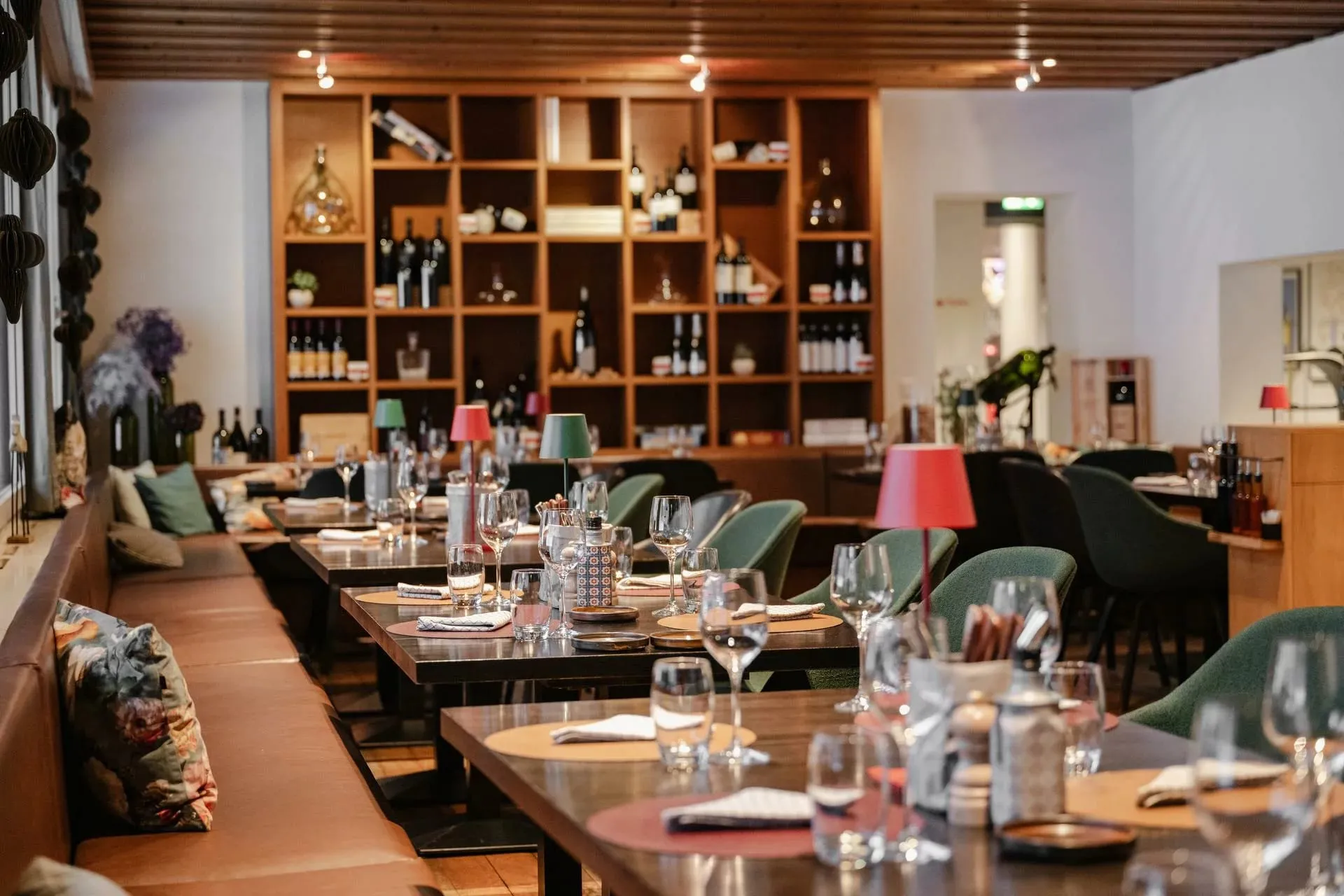 Salão elegante de restaurante com adega e mesas bem postas