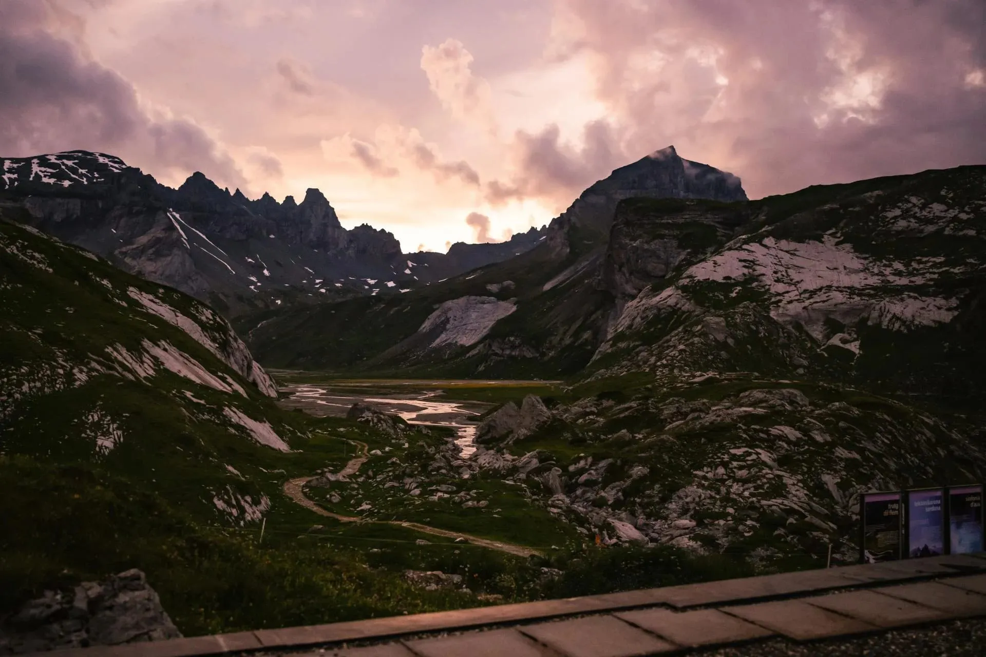 Pôr do sol dramático sobre vale alpino com montanhas nevadas