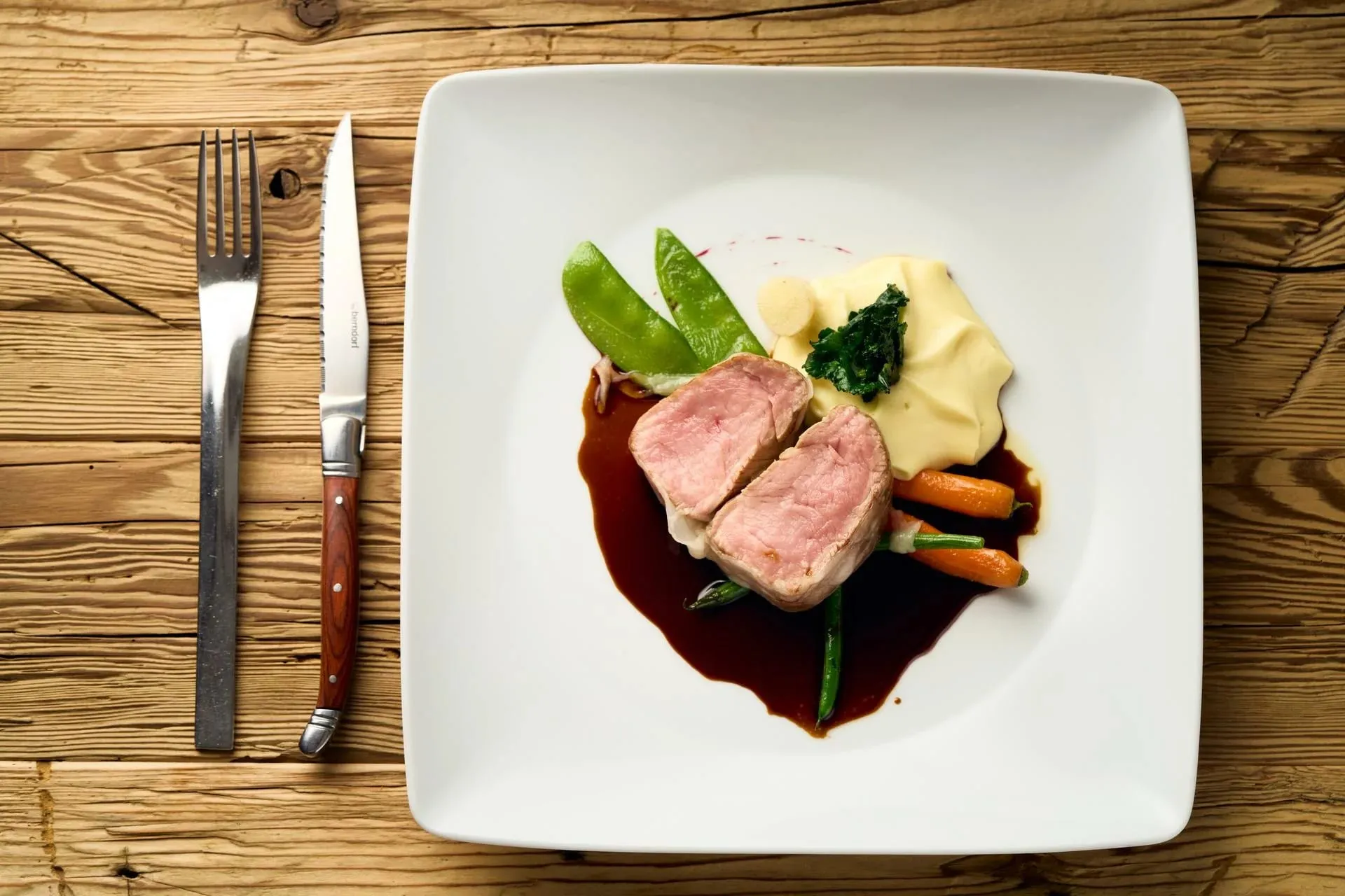 Prato de carne com purê e legumes em molho escuro