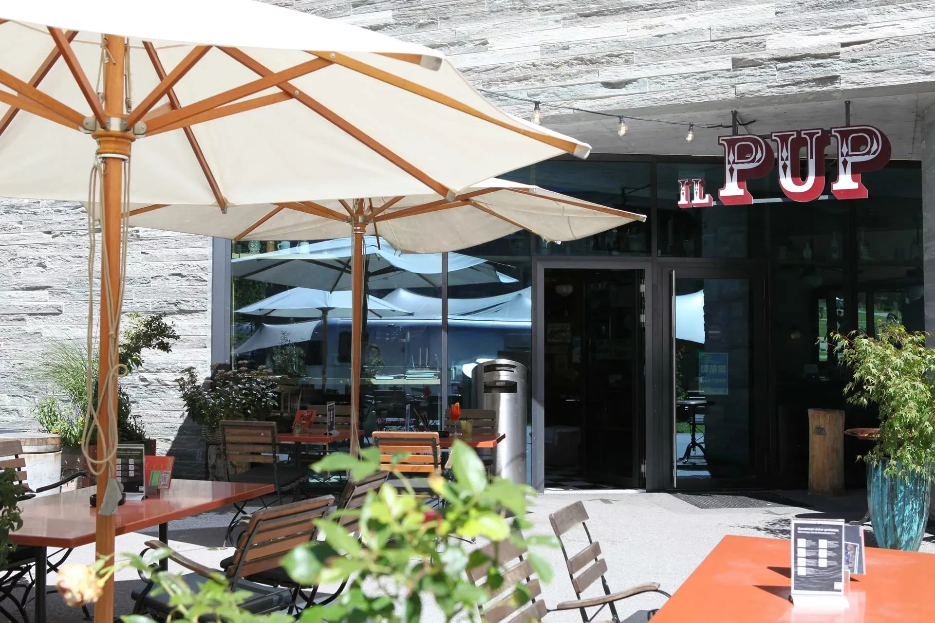 Terraço externo do restaurante Il Pup com mesas e guarda-sóis