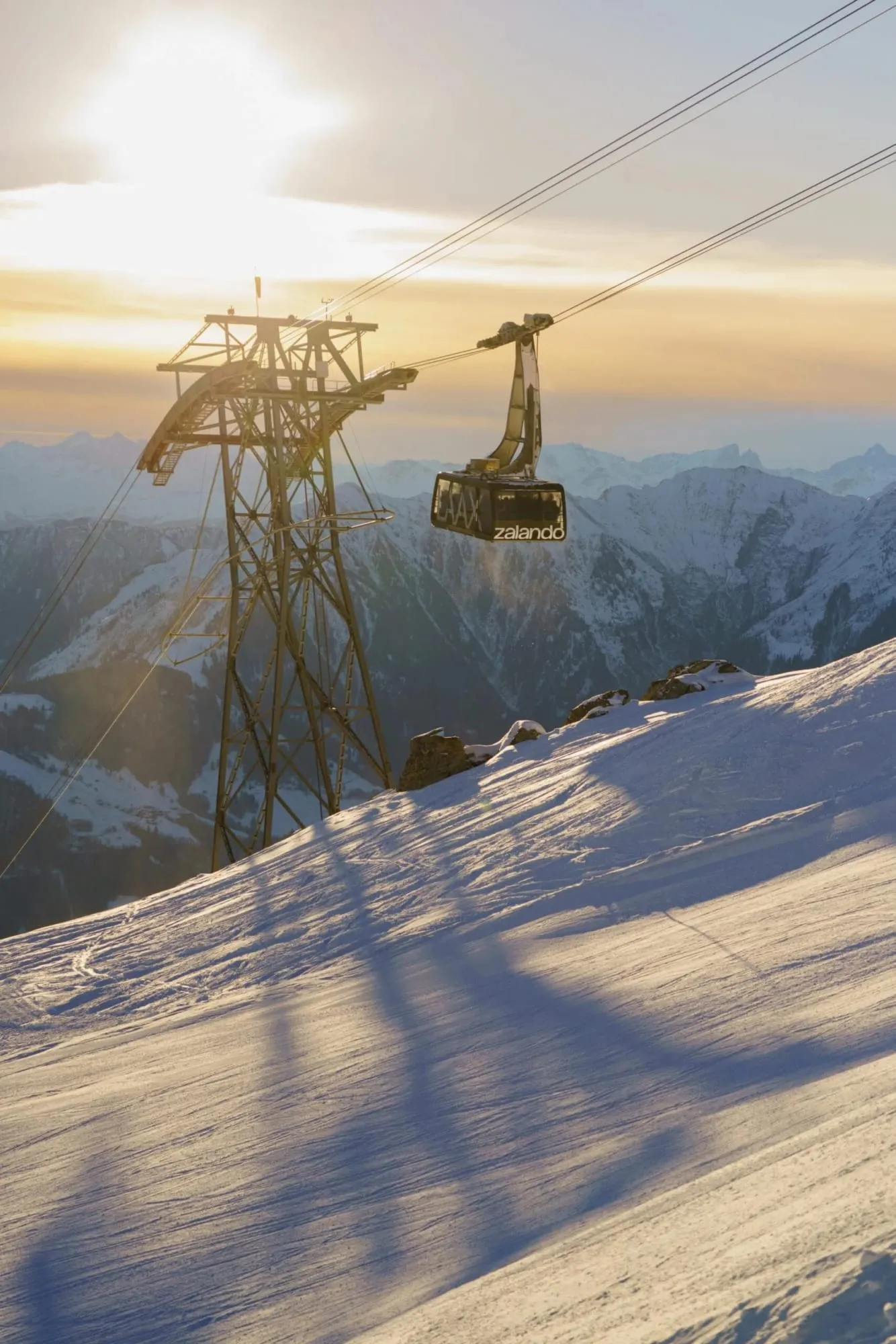Teleférico ao pôr do sol sobre montanhas cobertas de neve