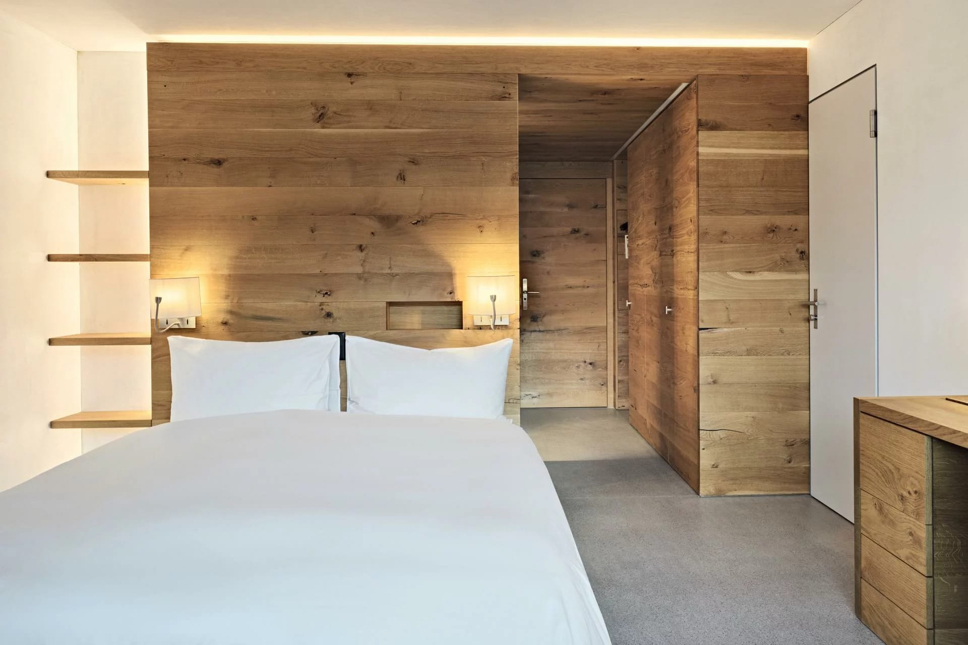 Quarto moderno com cabeceira em madeira clara e iluminação indireta