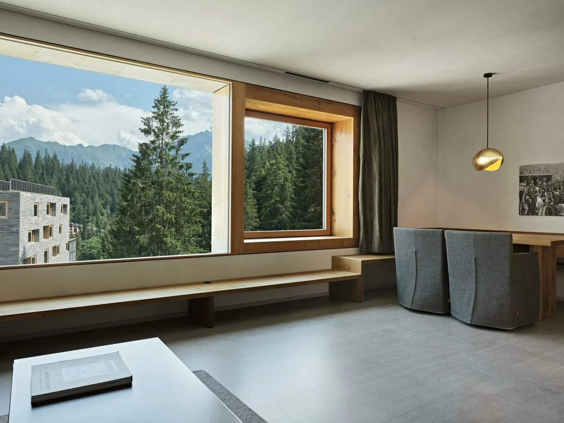 Sala com grande janela panorâmica enquadrando floresta e montanhas