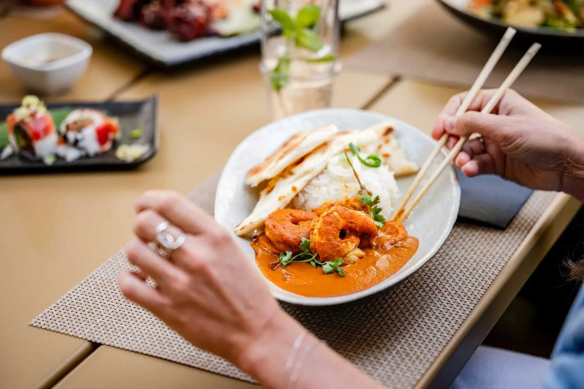 Prato de curry com camarão e arroz sendo servido com hashis