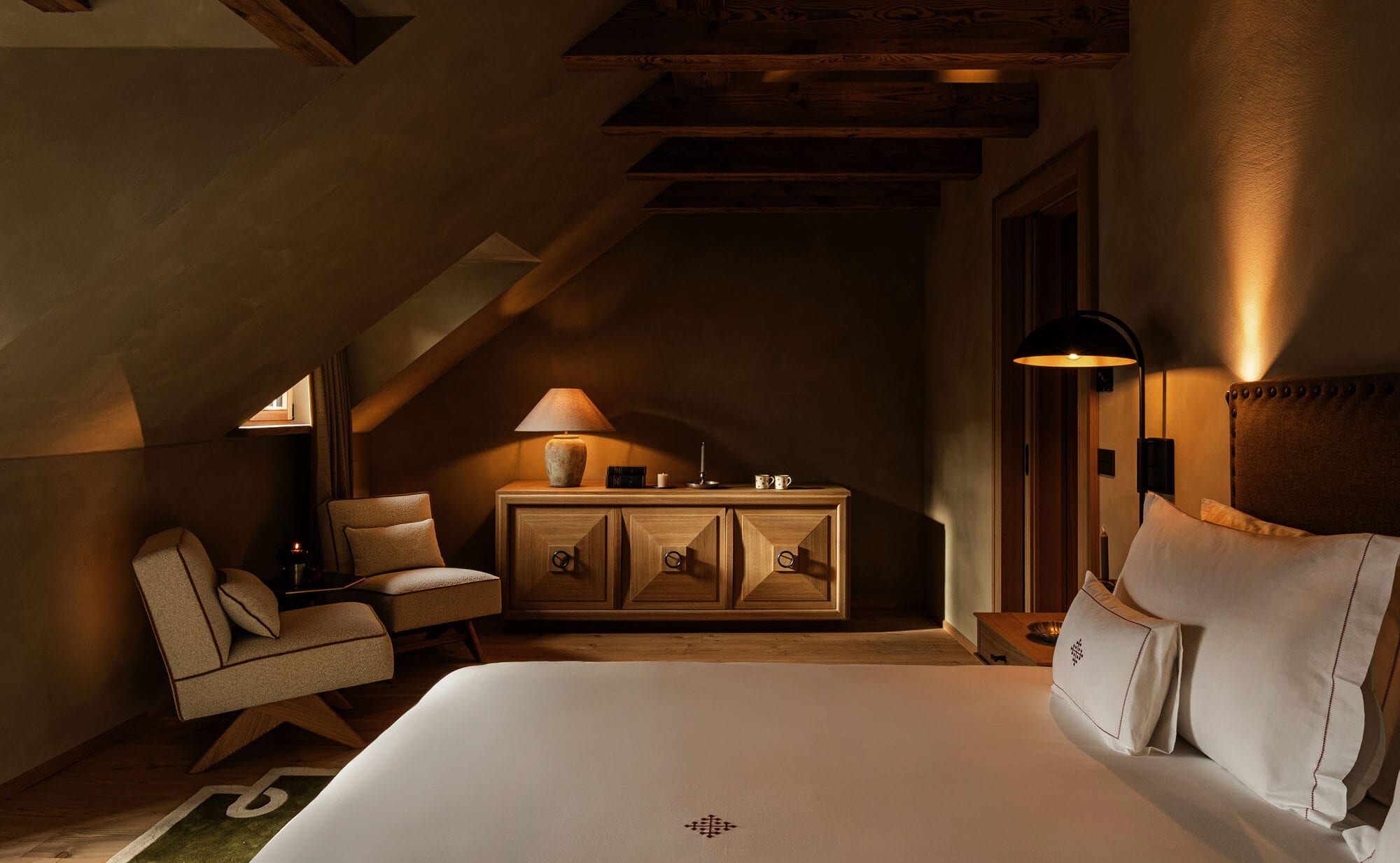 Quarto aconchegante com vigas de madeira e iluminação quente suave