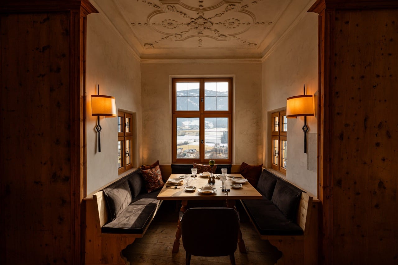 Sala de jantar íntima com teto estuque, mesa posta e janela alpina