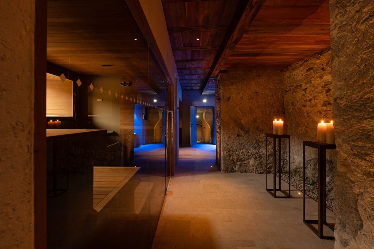 Corredor do spa com velas e paredes de pedra iluminadas em azul
