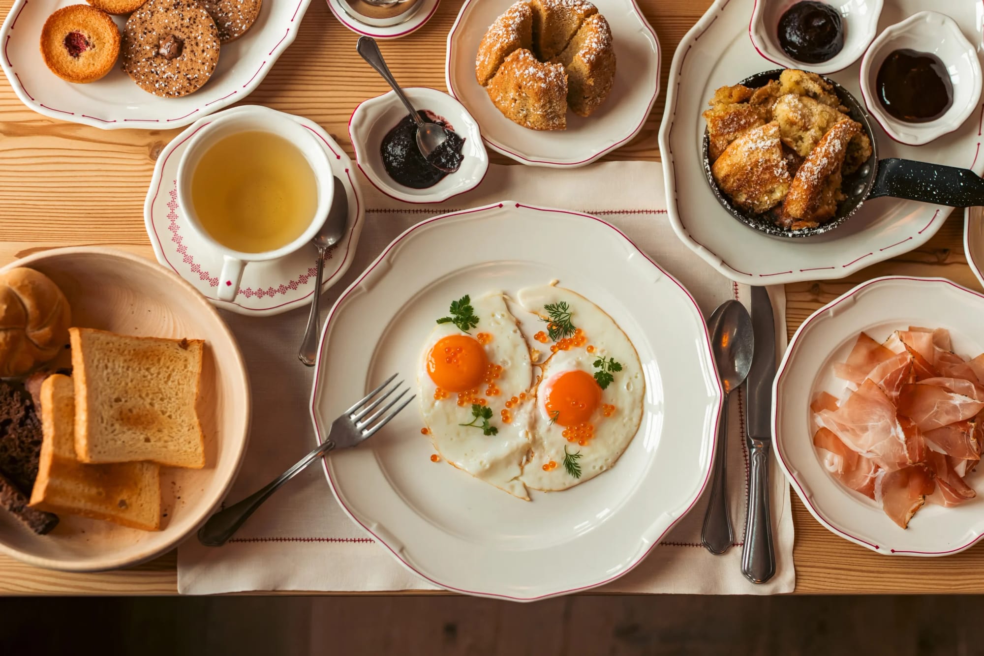 Café da manhã farto com ovos, presunto, pães e bolos artesanais