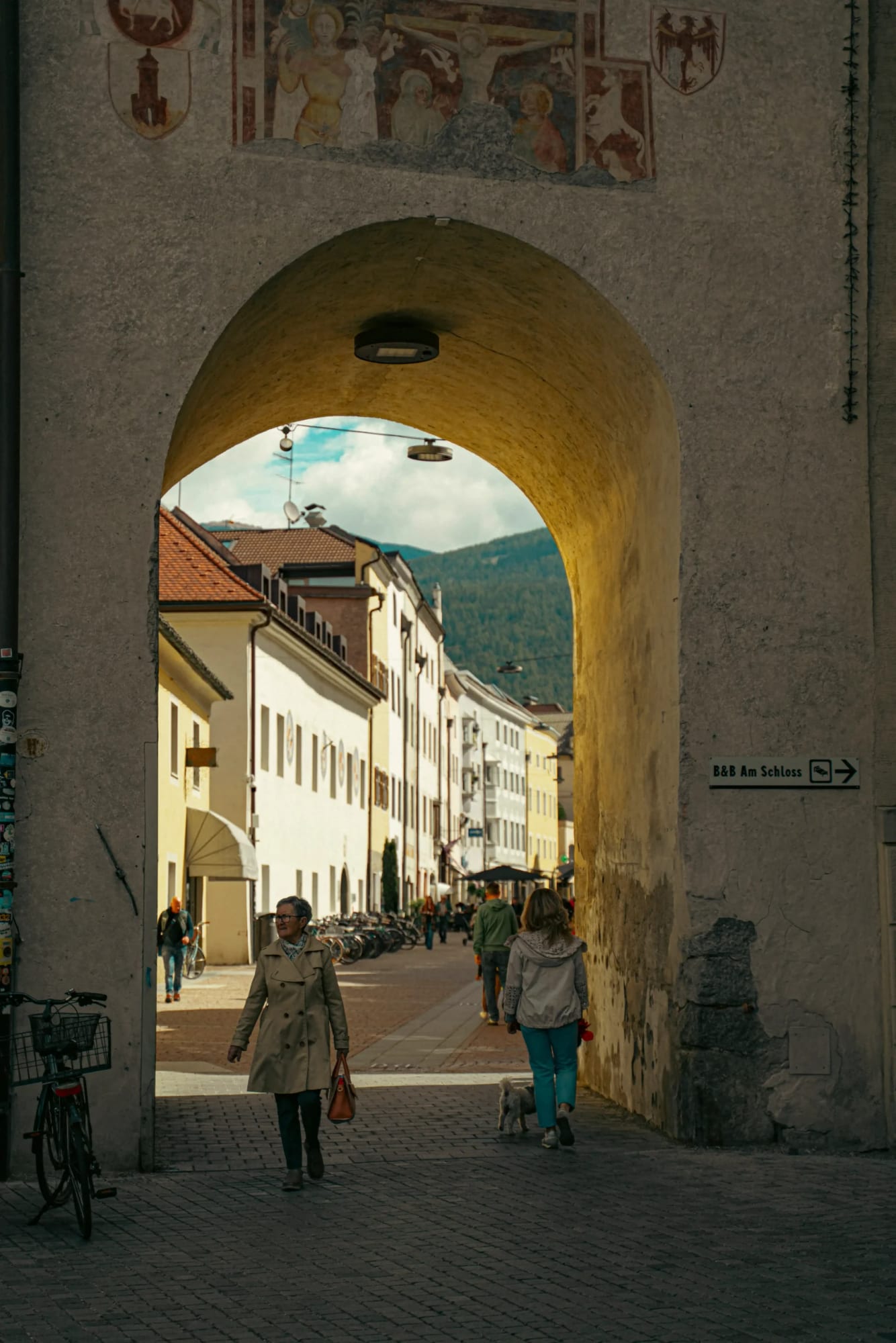 Arco histórico com afrescos dando vista para rua alpina