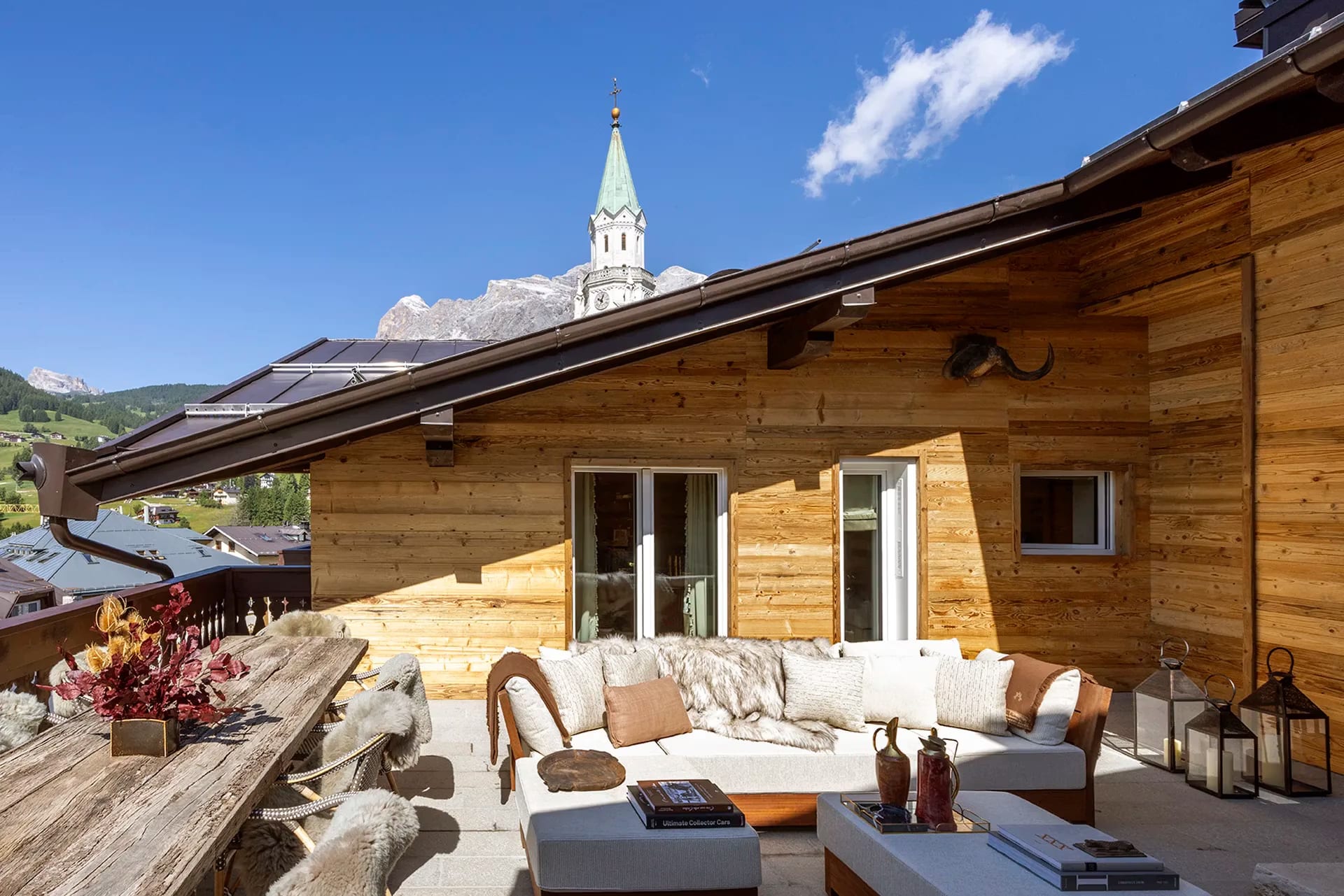 Terraço de chalé com sofá branco e vista para campanário alpino