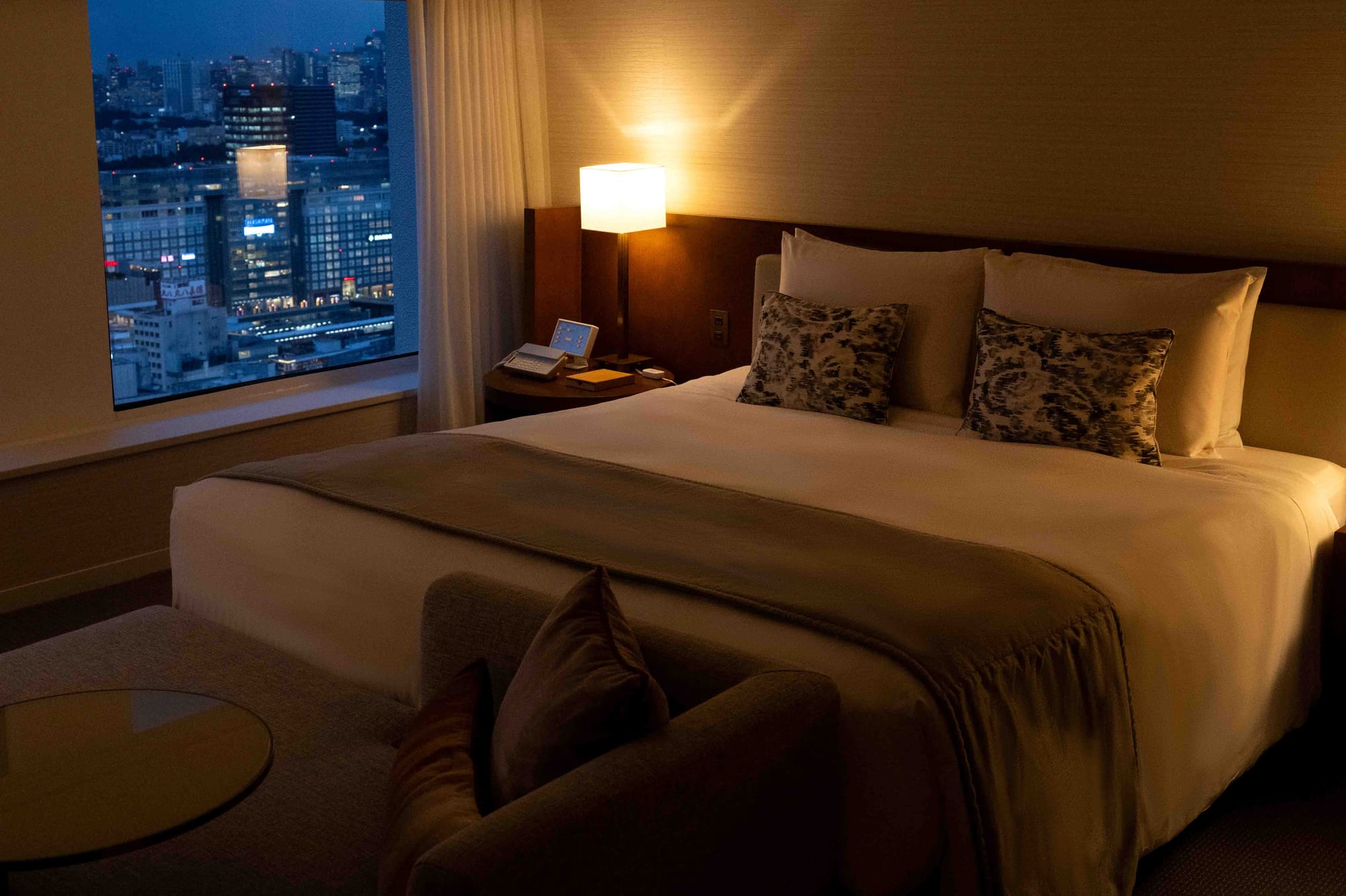 Quarto escuro e aconchegante com cama e vista noturna da cidade