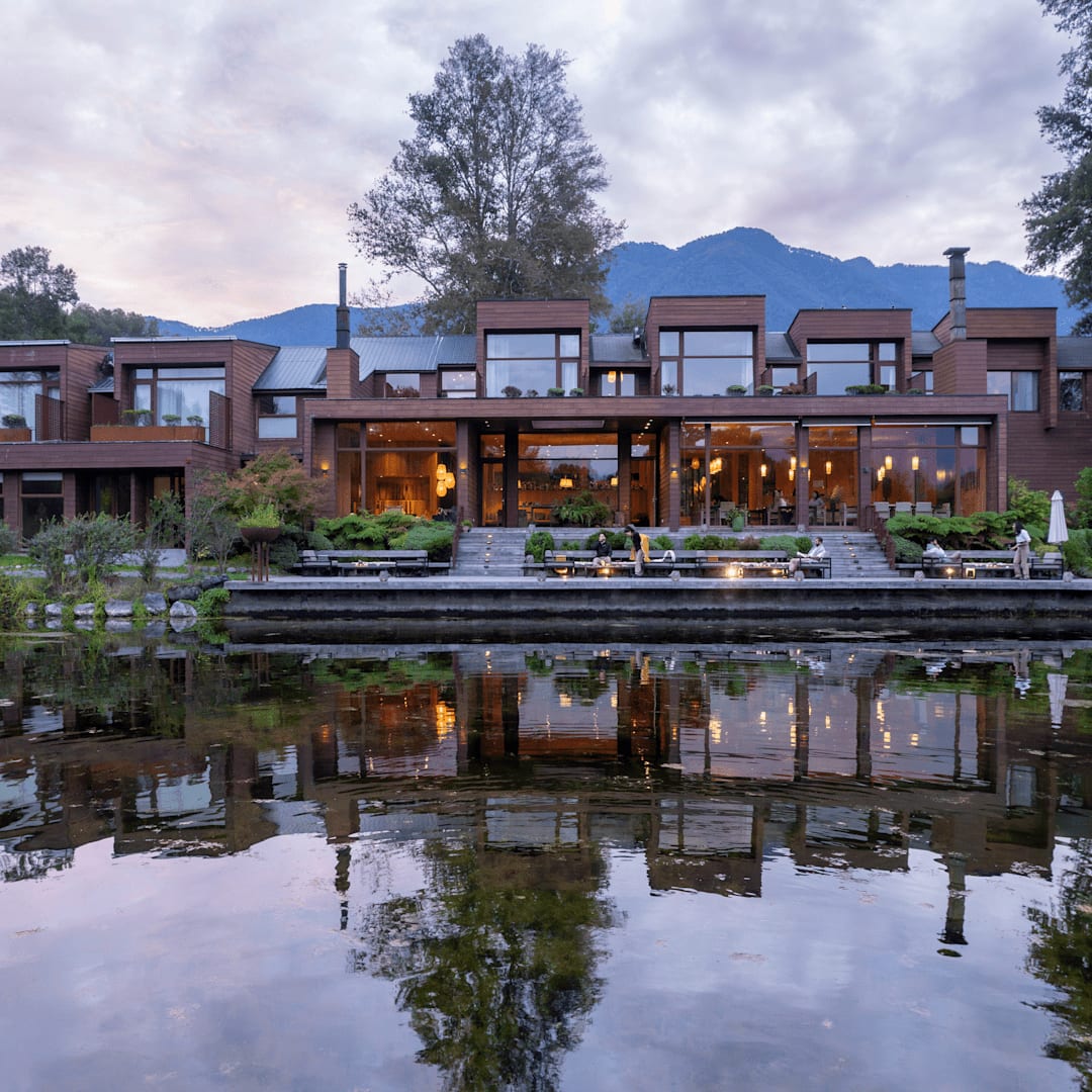 Fachada iluminada do hotel Vira Vira refletida na lagoa ao entardecer