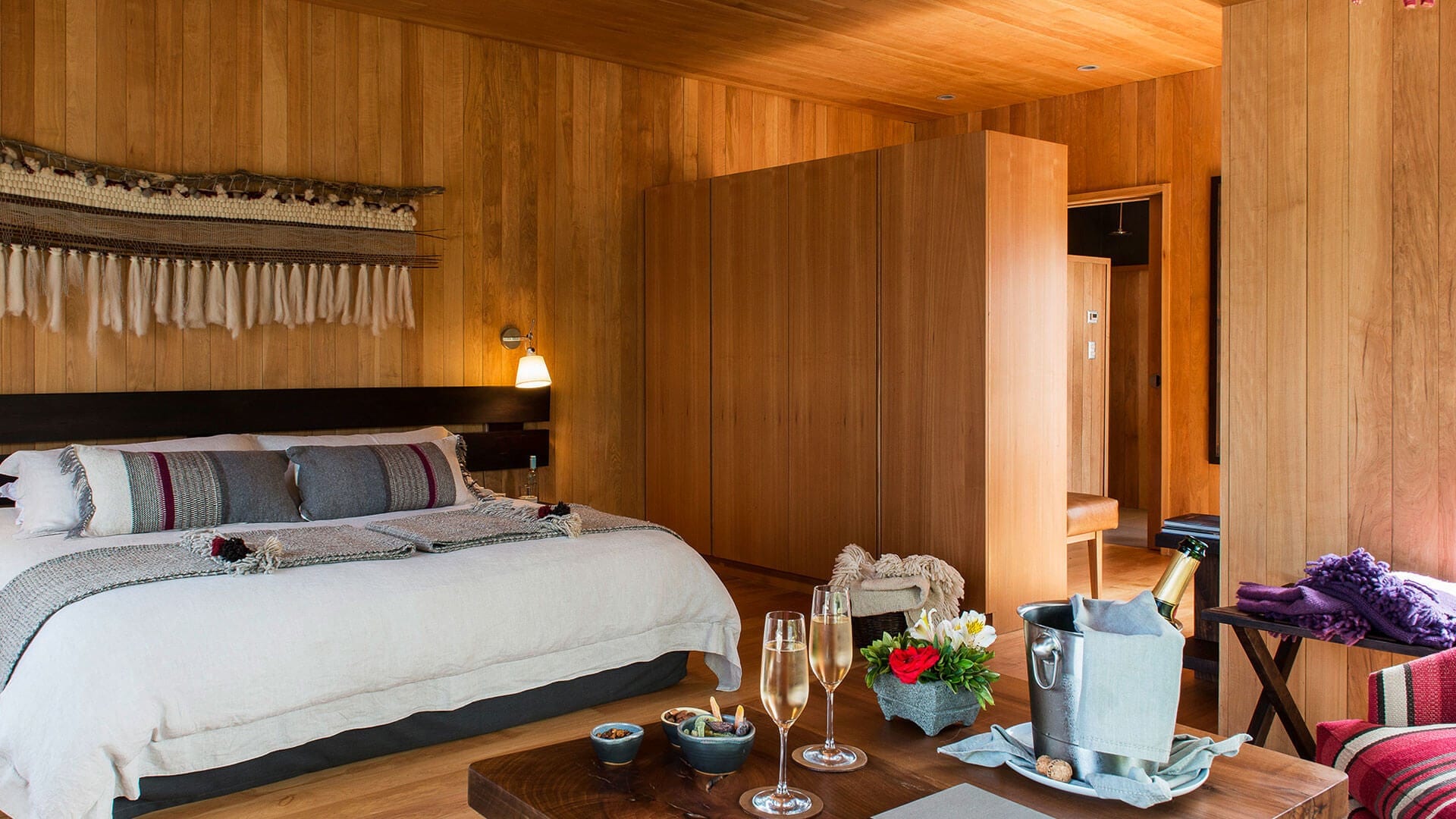 Quarto luxuoso com cama king, taças de champanhe e decoração em madeira