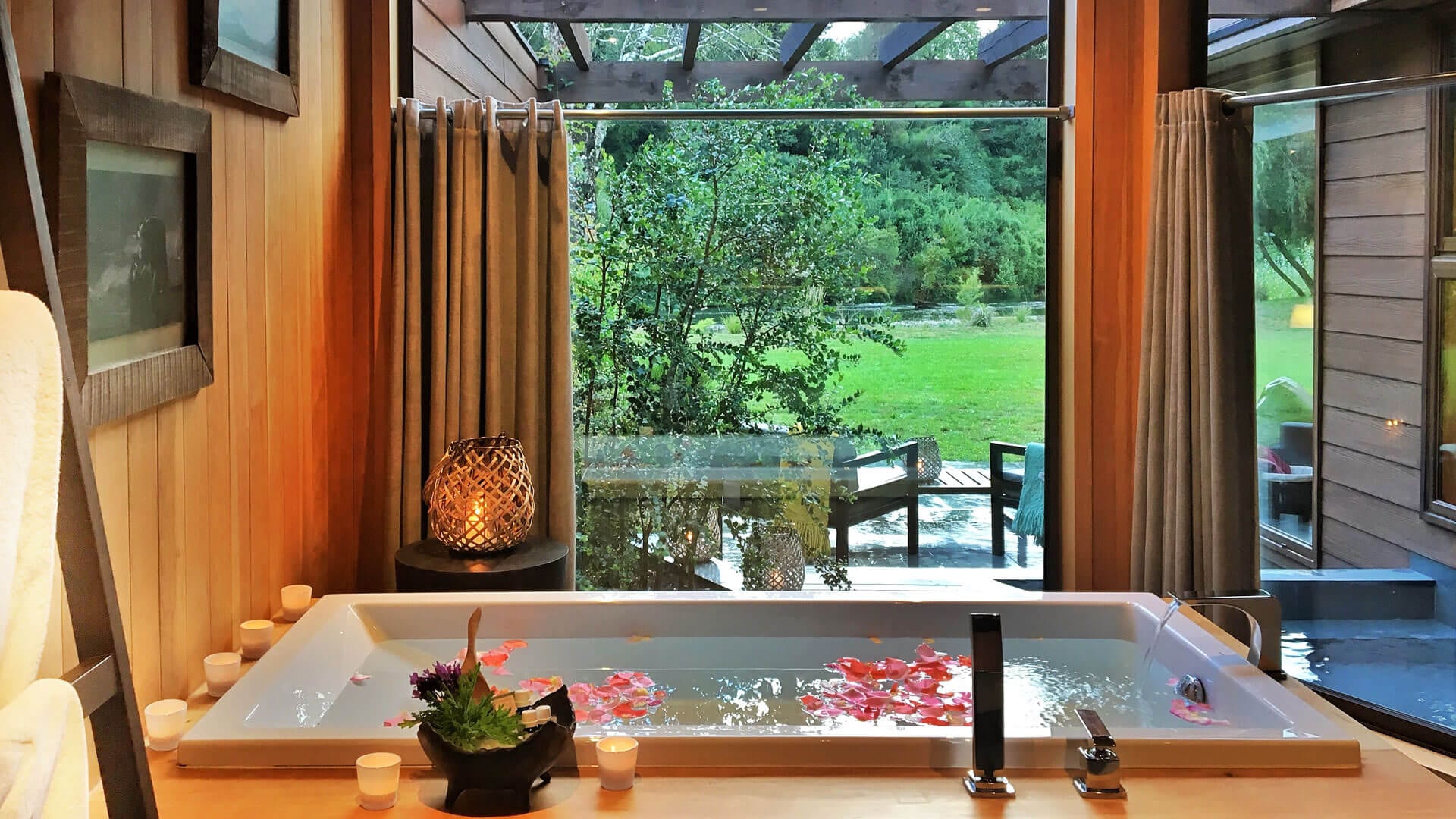 Banheira com flores e velas com vista para o jardim verde do hotel