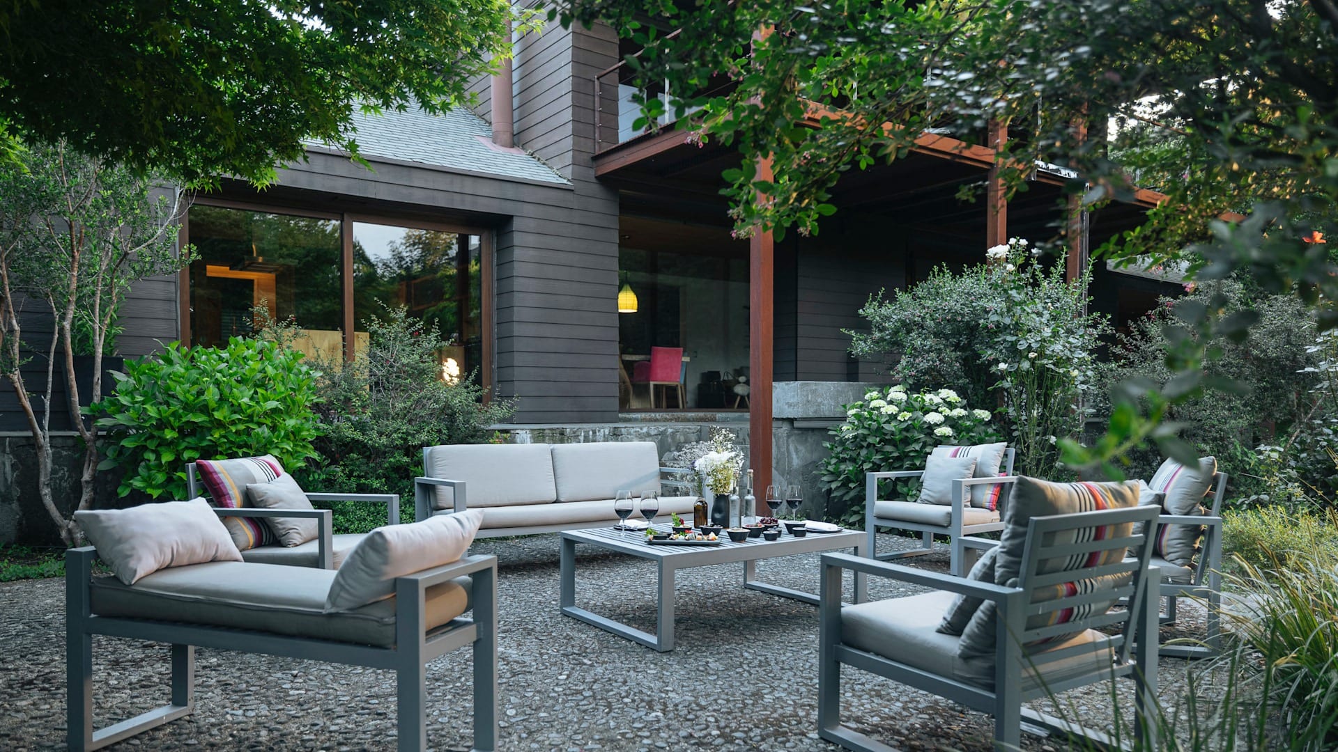 Área de estar externa com mobiliário moderno e jardim do hotel