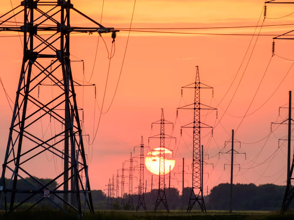 Pylons stretching into distance against amber sunset