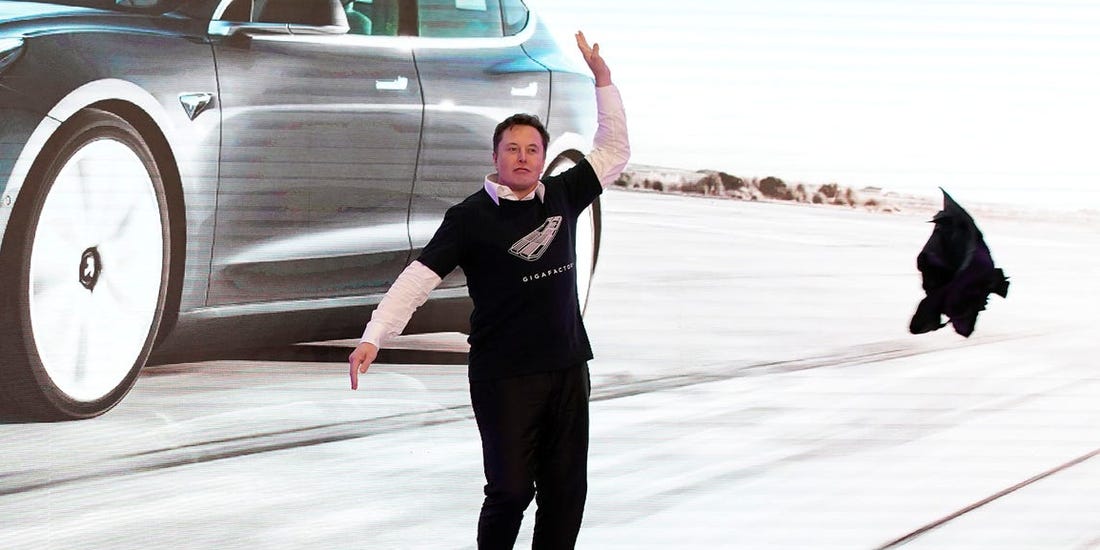 Man dancing beside large image of a Tesla car, throwing black jacket in the air.
