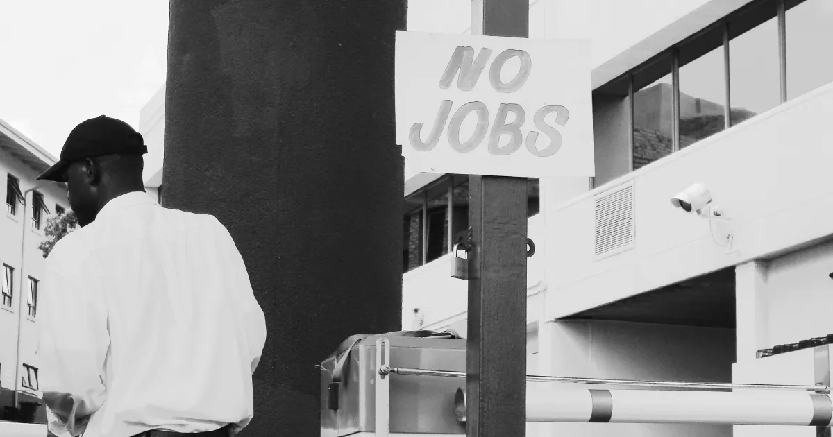 A man is turned away, despondent. There are no jobs according to the sign