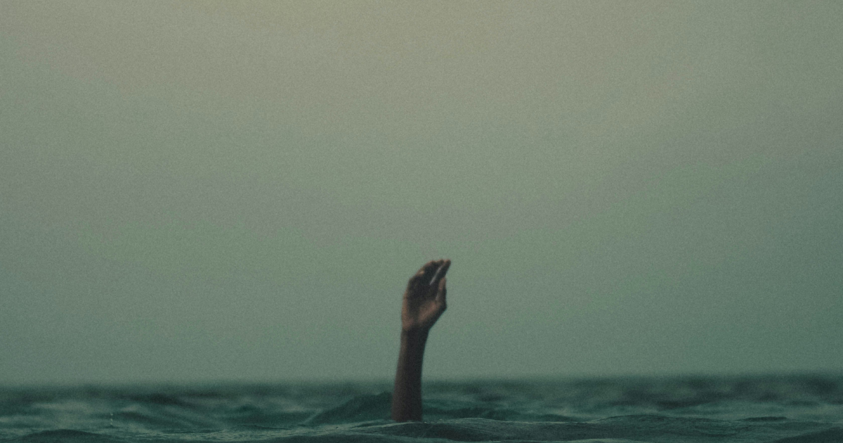 Hand reaching out from underwater, person overwhelmed