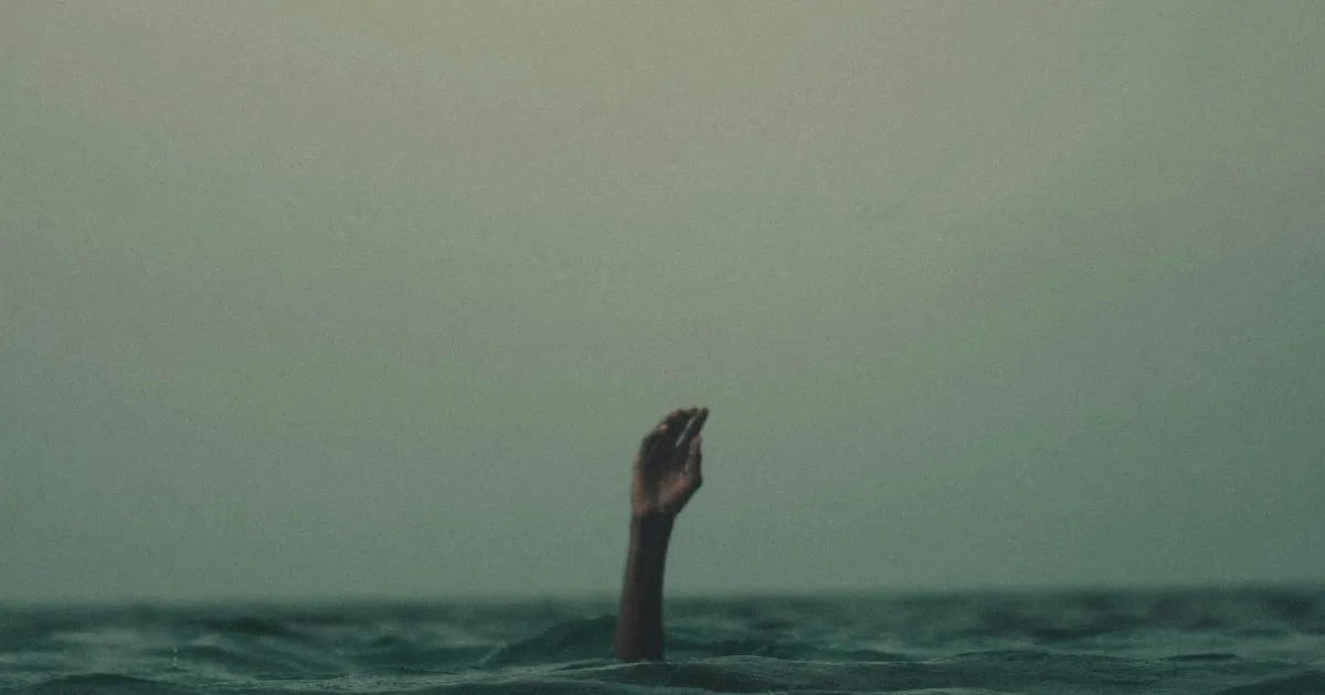 Hand reaching out from underwater, person overwhelmed