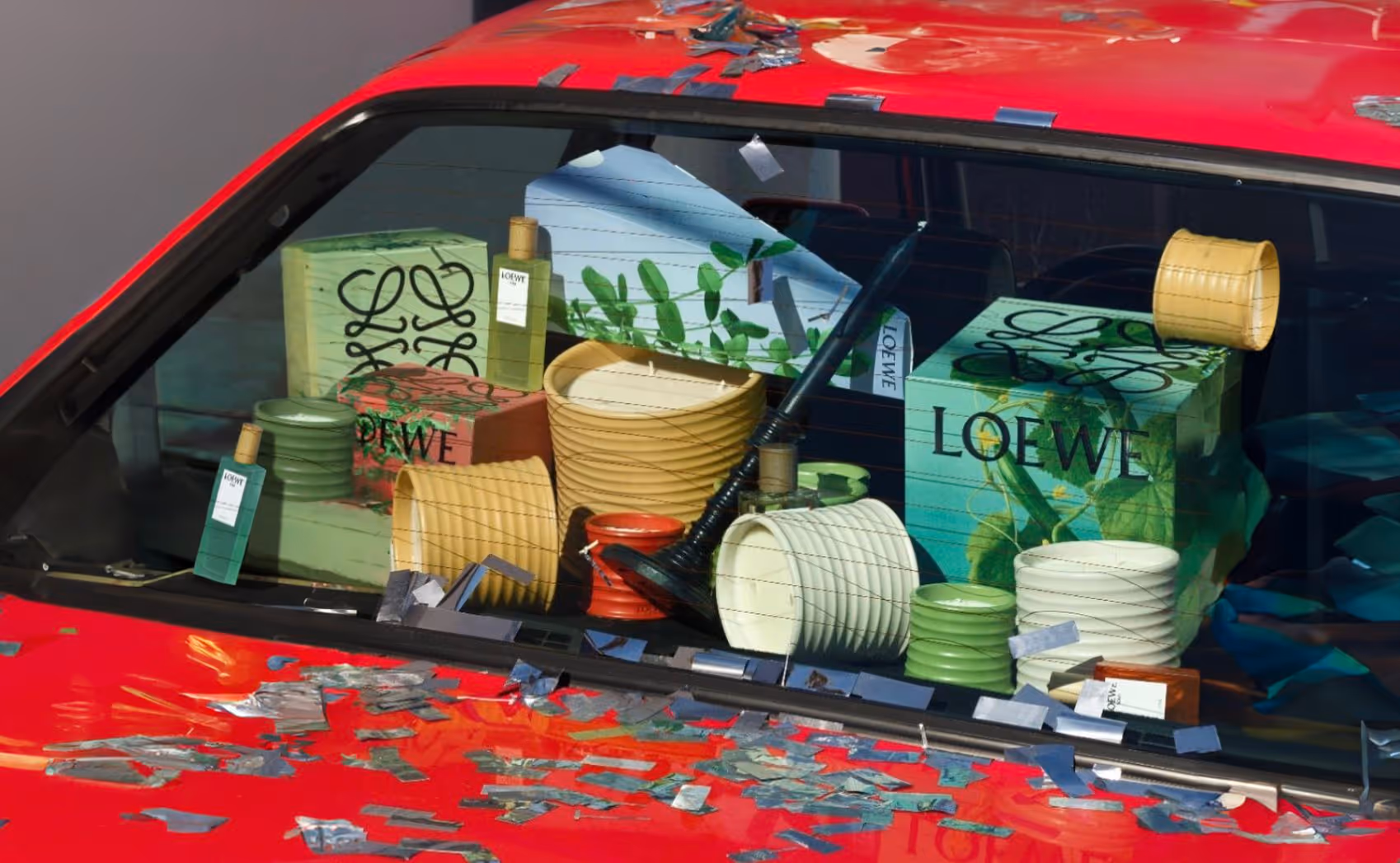 Ventana trasera del automóvil está repleta de productos de Loewe. Desde perfumes hasta velas.
