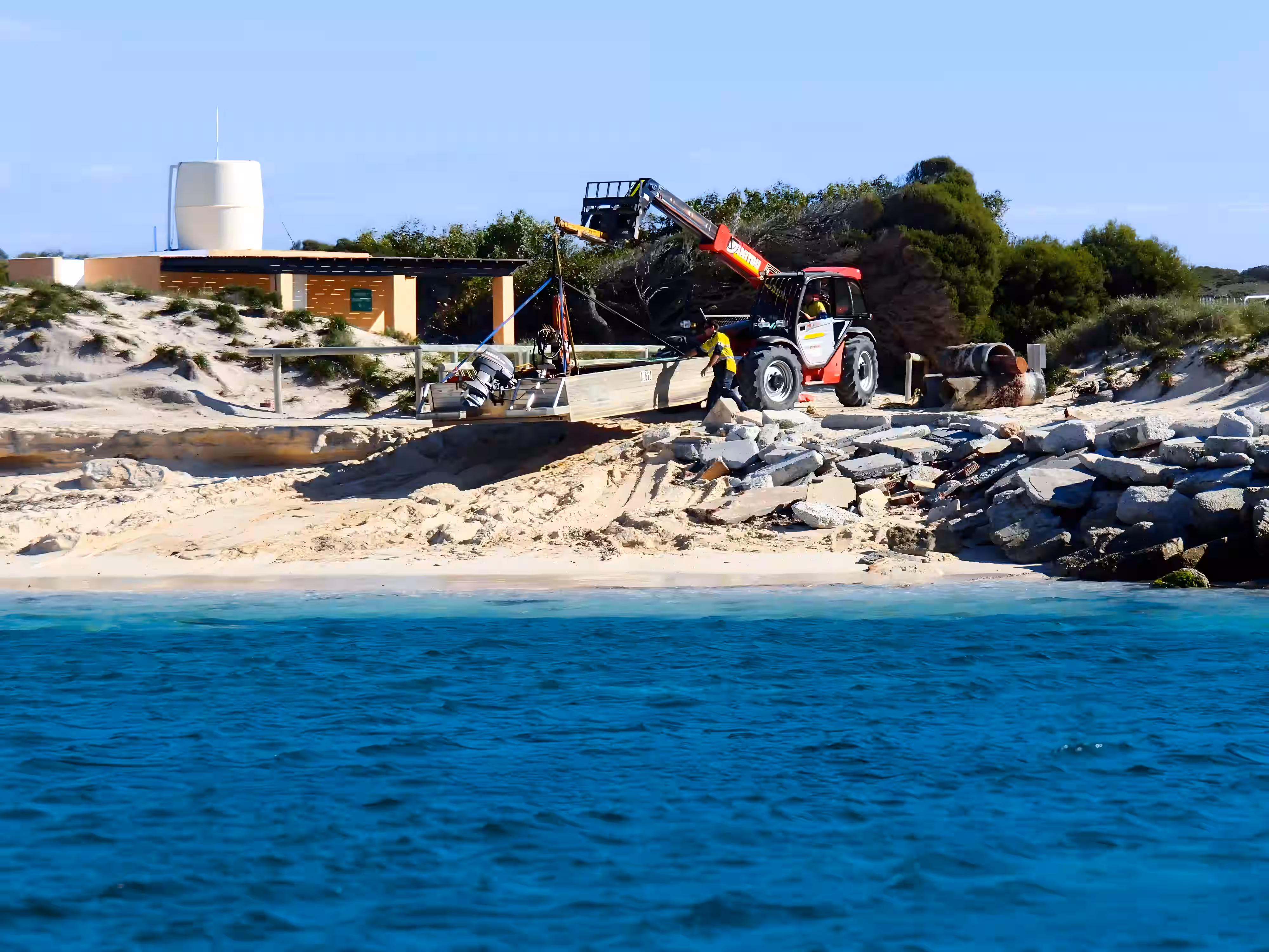 Team using a telehandler to lift and position equipment during coastal marine works