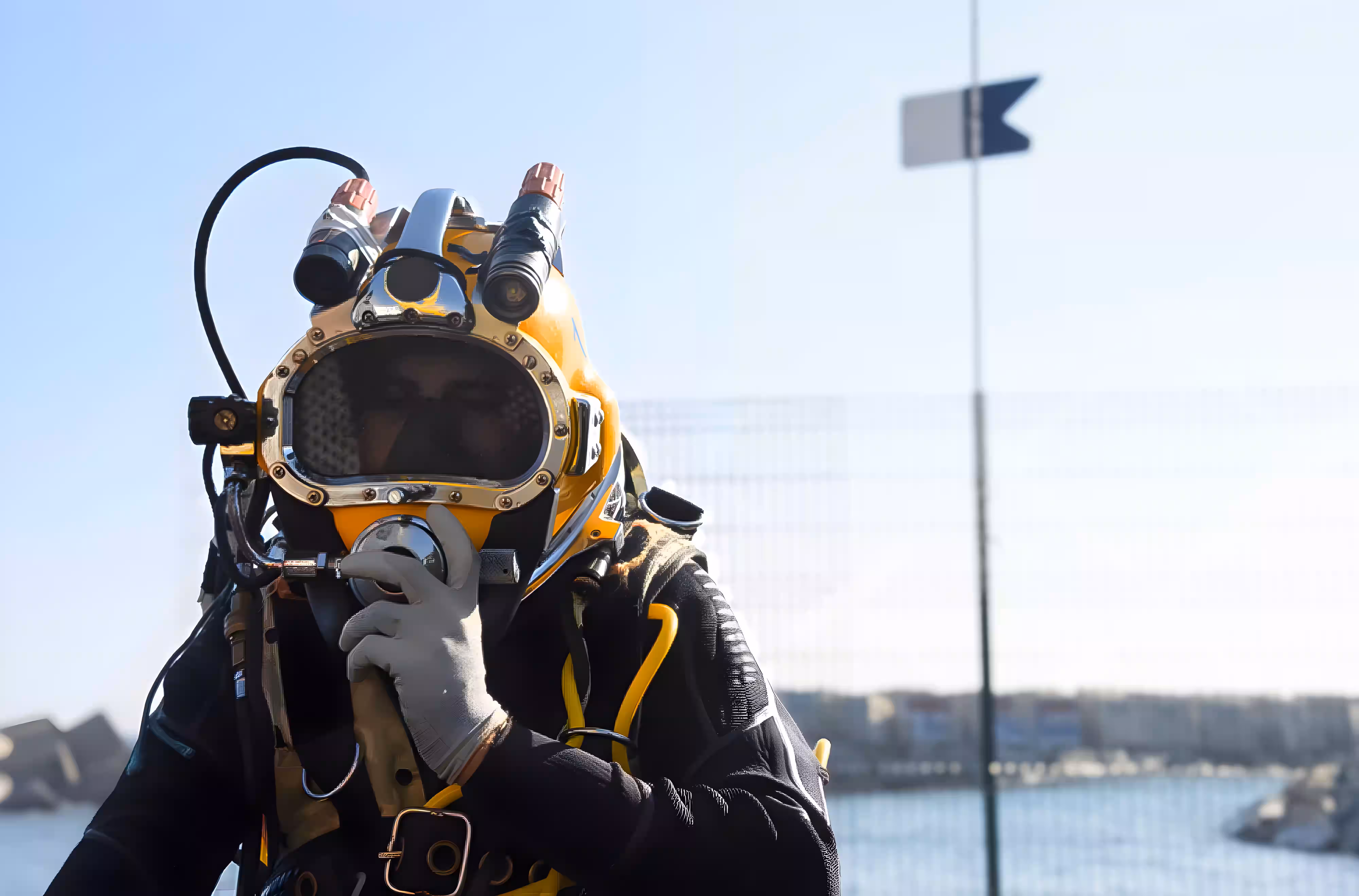 Commercial diver wearing a surface-supplied diving helmet at waterside location