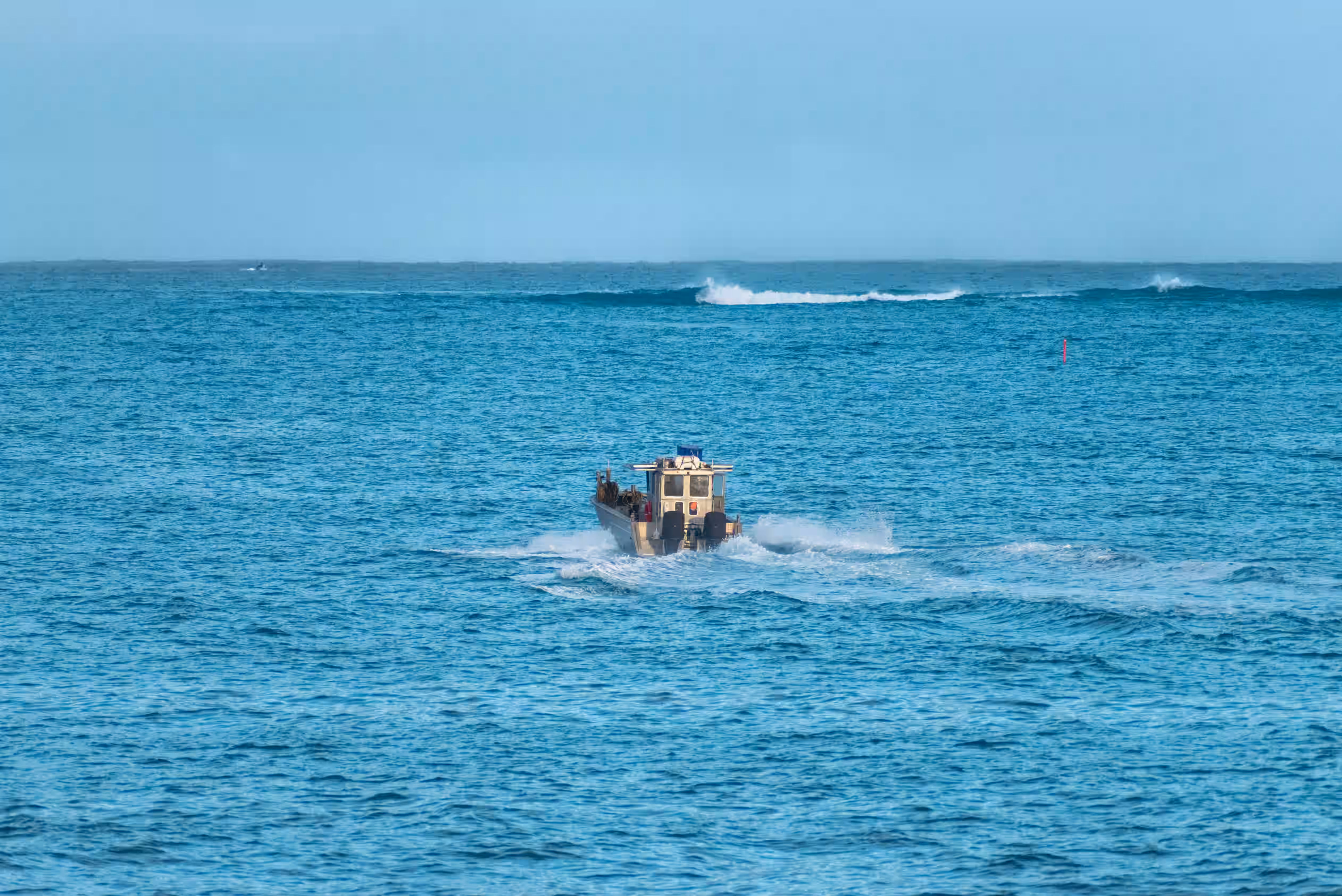 A floating platform being towed through water with a bridge in the background