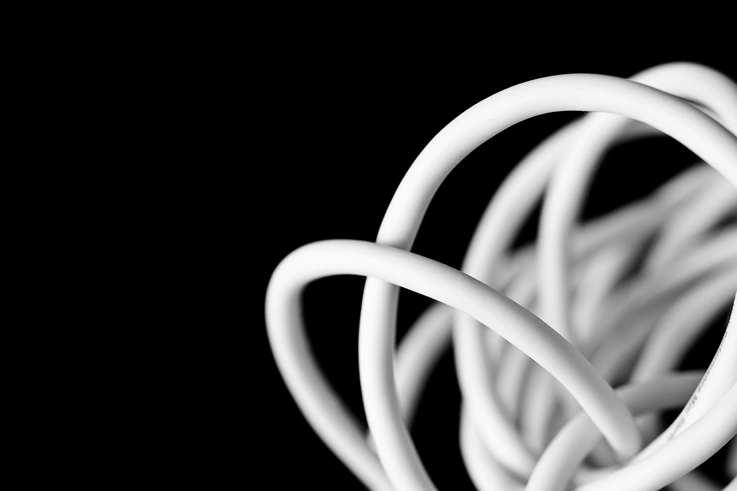 A tangled white cable coiled against a black background