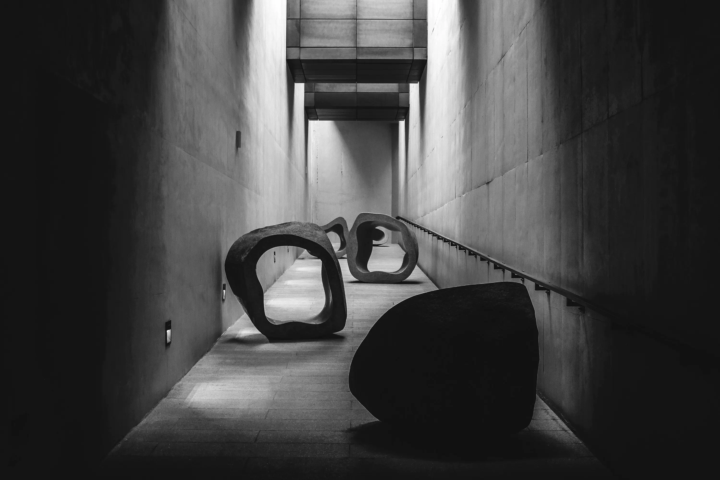 Large abstract stone sculptures blocking a narrow concrete corridor