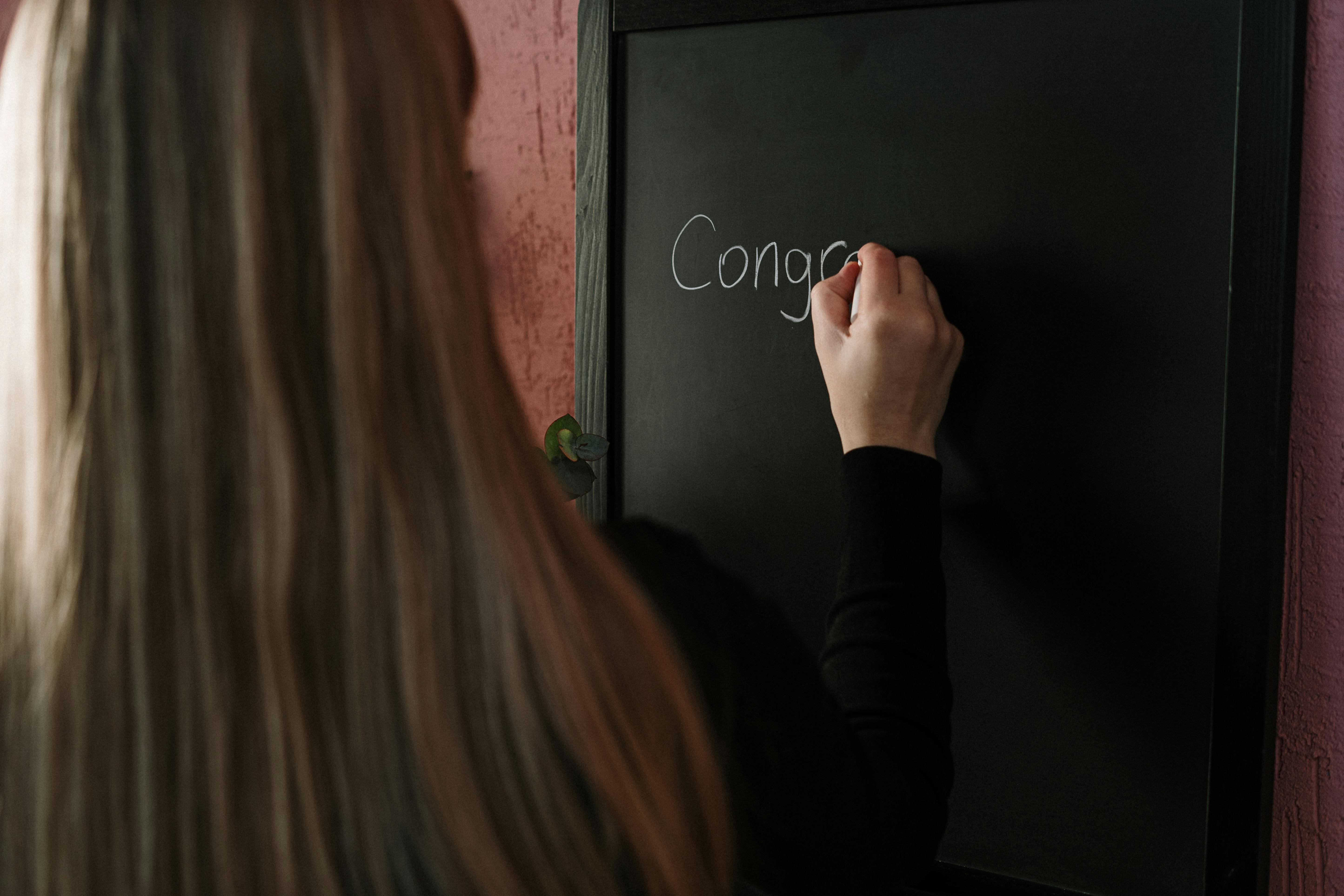 A girl writing congrats on the table