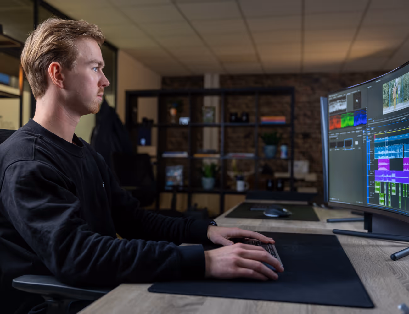 Een foto waar Jochem achter een computer een video aan het bewerken is.