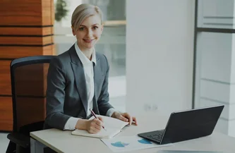 Femme professionnelle en costume au travail à son bureau, ordinateur portable ouvert, ambiance cabinet juridique.