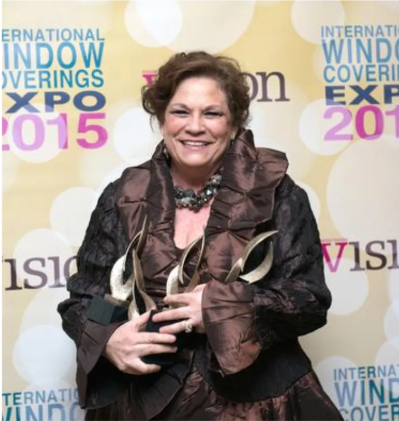 A woman standing in front of a wall holding an award.