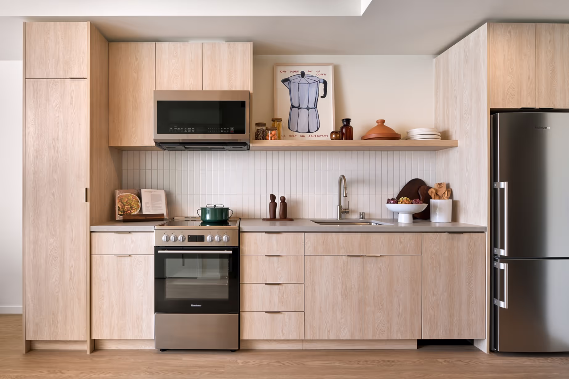 Isle House high-end apartments interior of the kitchen with light wood cabinets and stainless steel appliances.