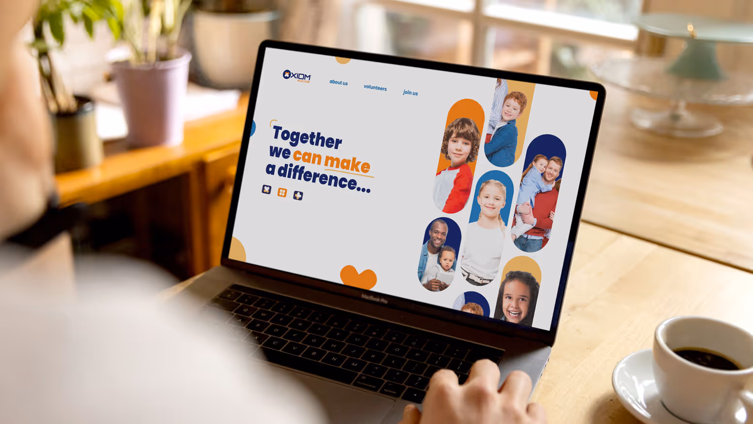 Laptop screen displaying a website for Axiom’s charitable initiative featuring children’s photos and the tagline ‘Together we can make a difference…’ aimed at encouraging community participation.