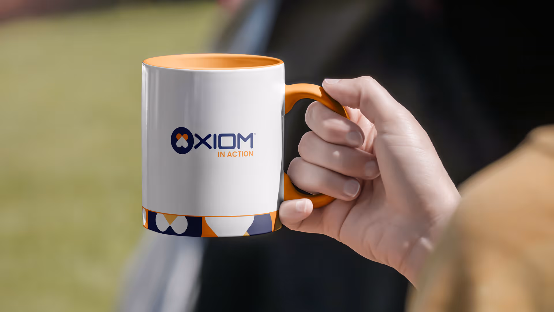 A hand holding a coffee mug with the organization's branding, symbolizing warmth and support within the community.