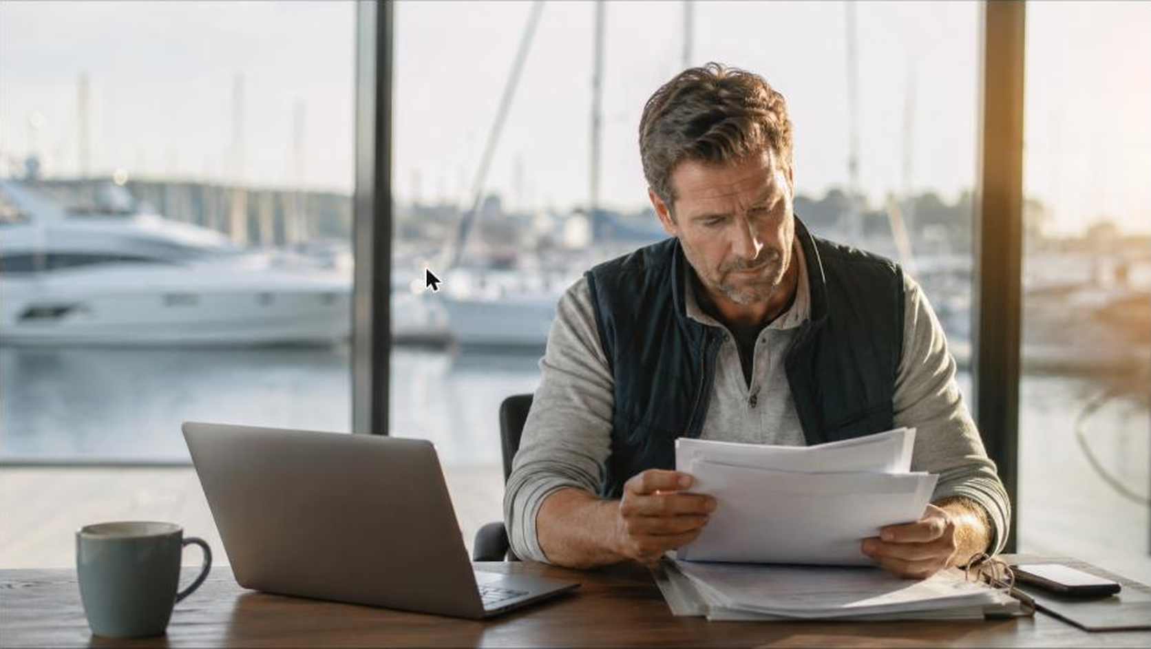 Marina office manager reviewing job and billing information at a desk overlooking the marina