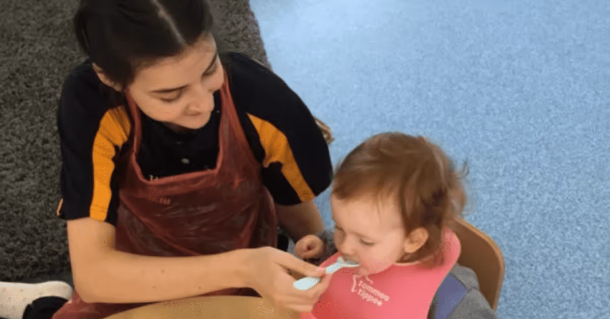 Nursery room leader feeding child