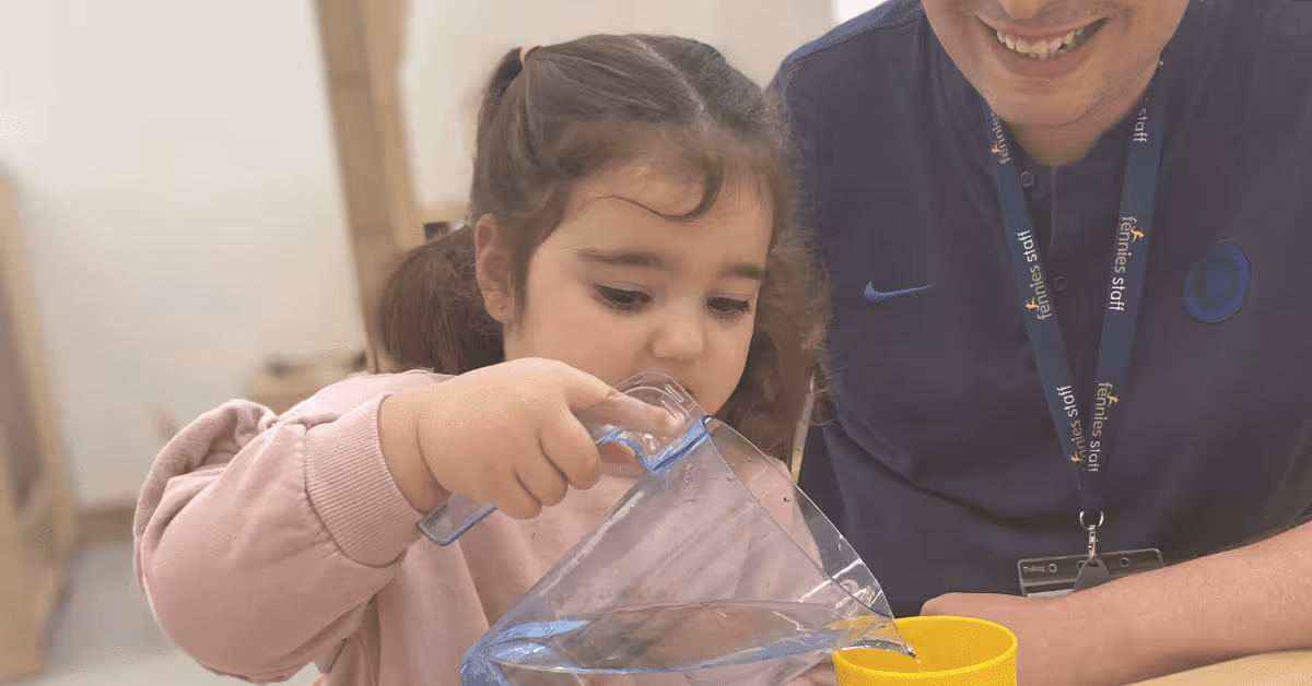 child pouring a glass of water with early years teacher