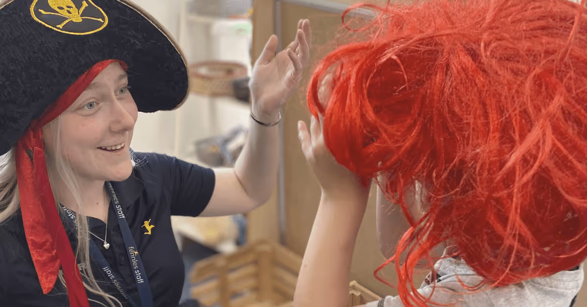Early years teacher dressing up with child