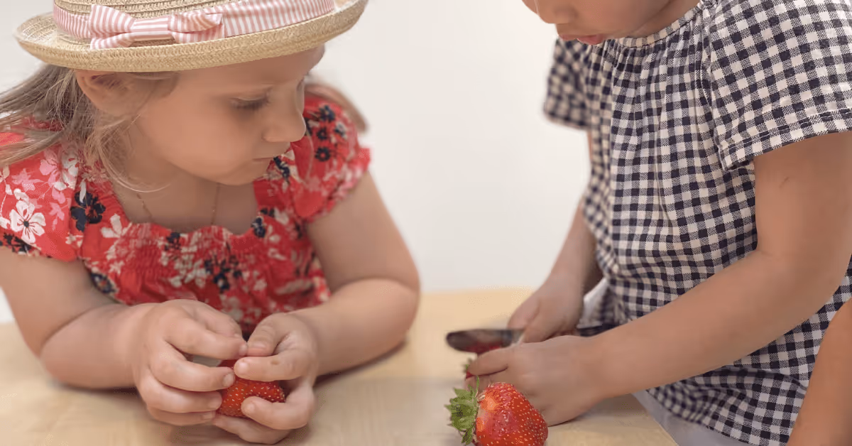 children cutting strawberries together in nursery