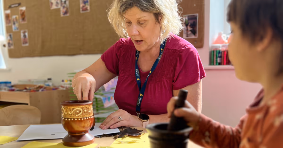 early years teacher talking to child sitting at a table