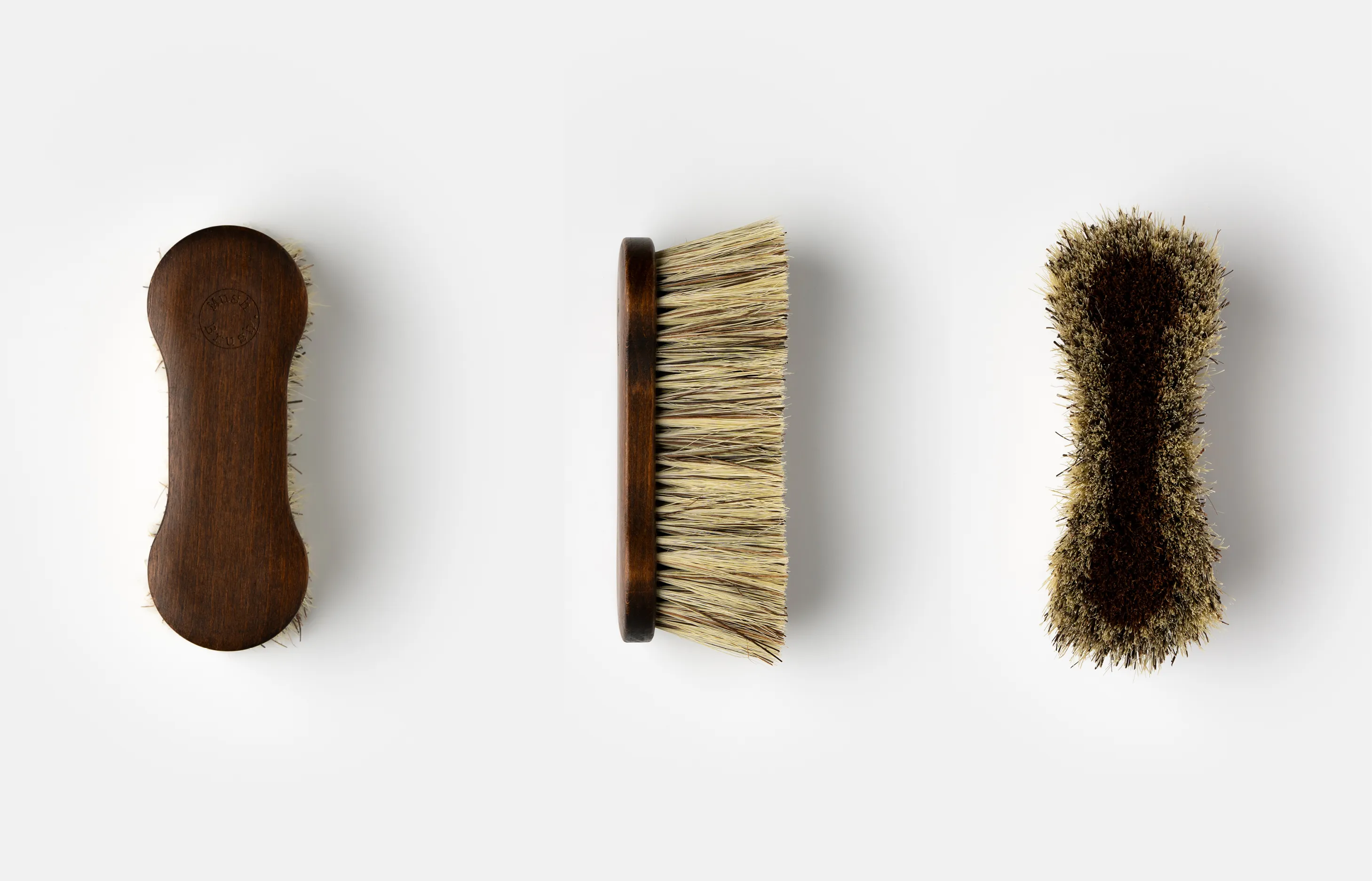 Two hands holding up a wooden last under the lights to inspect its shape and quality.