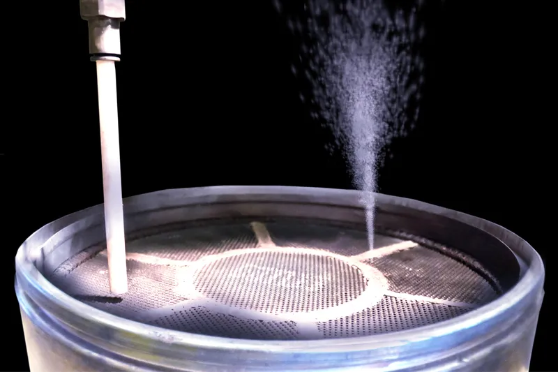 Diesel particulate filter cleaning with spray nozzle blasting soot from circular DPF core.