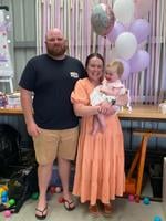 Smiling family of four at the beach with clear blue sky and calm sea in the background.