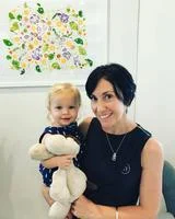 Smiling family of four at the beach with clear blue sky and calm sea in the background.