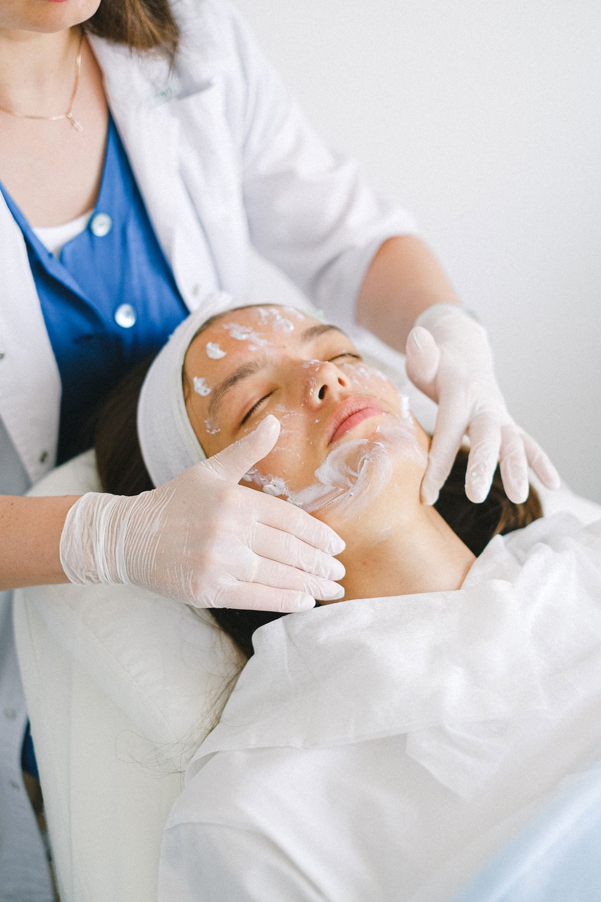 Skincare professional examining a patient's skin during a treatment
