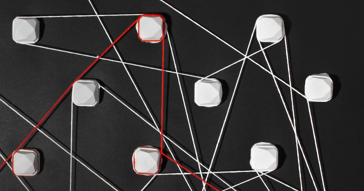 Síť propojených elementů na černém pozadí propletená různými spojnicemi s jednou hlavní určující červenou linkou.